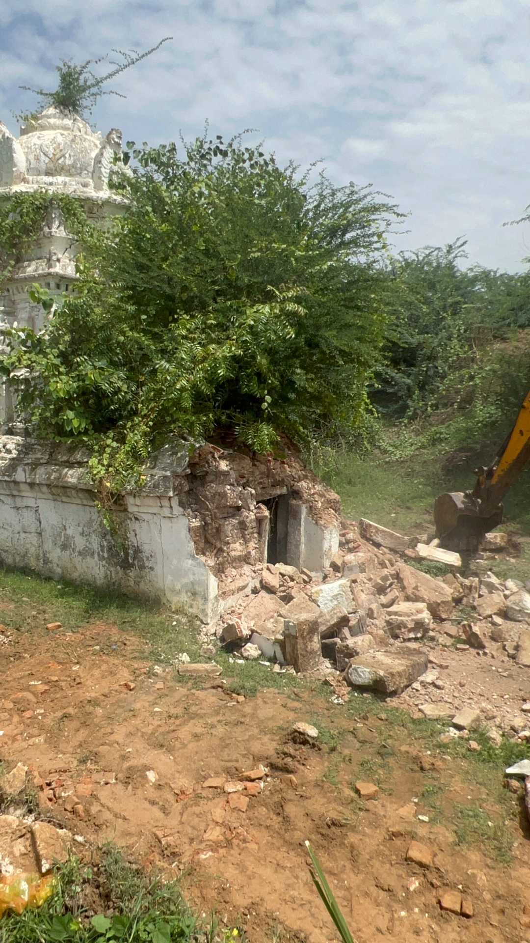 Old temple structure being demolished with an excavator